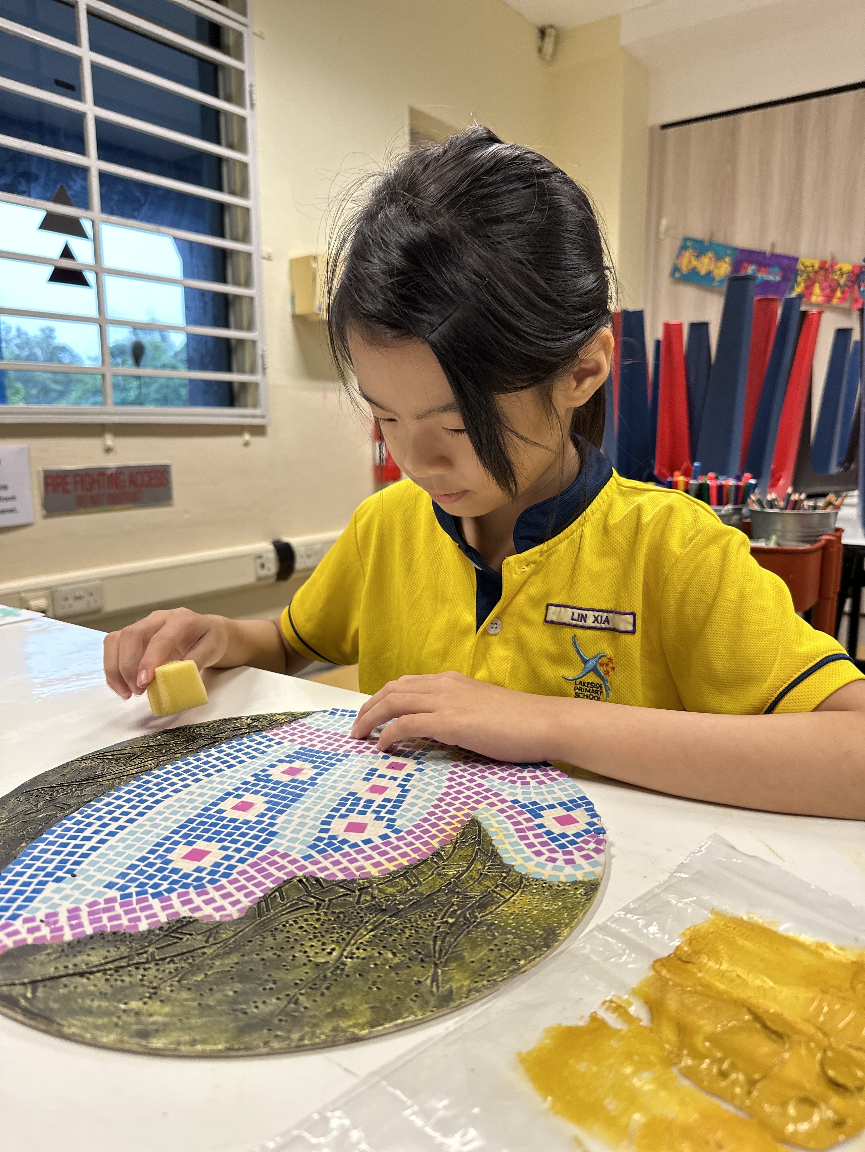 A student putting finishing touches to her mosaic artwork